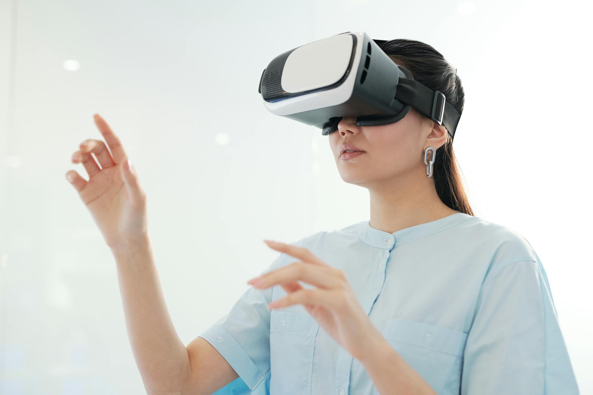Adult woman experiencing virtual reality using a headset indoors, gesturing with hands.